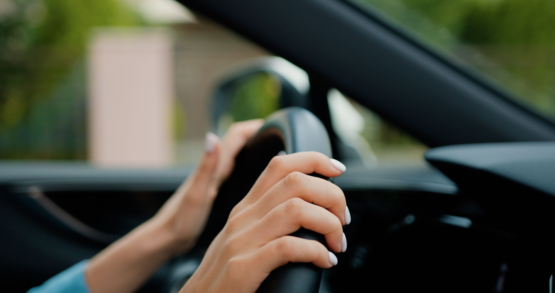 Close-up. Woman hands touching on steering wheel. Famale driver sits in car. City travelling on the road concept.